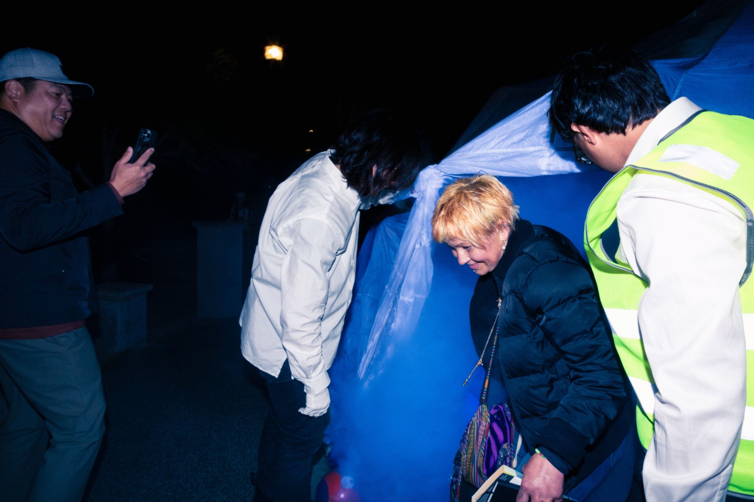 A participant in white emerging from HoloDome2 past a crew member in a safety vest