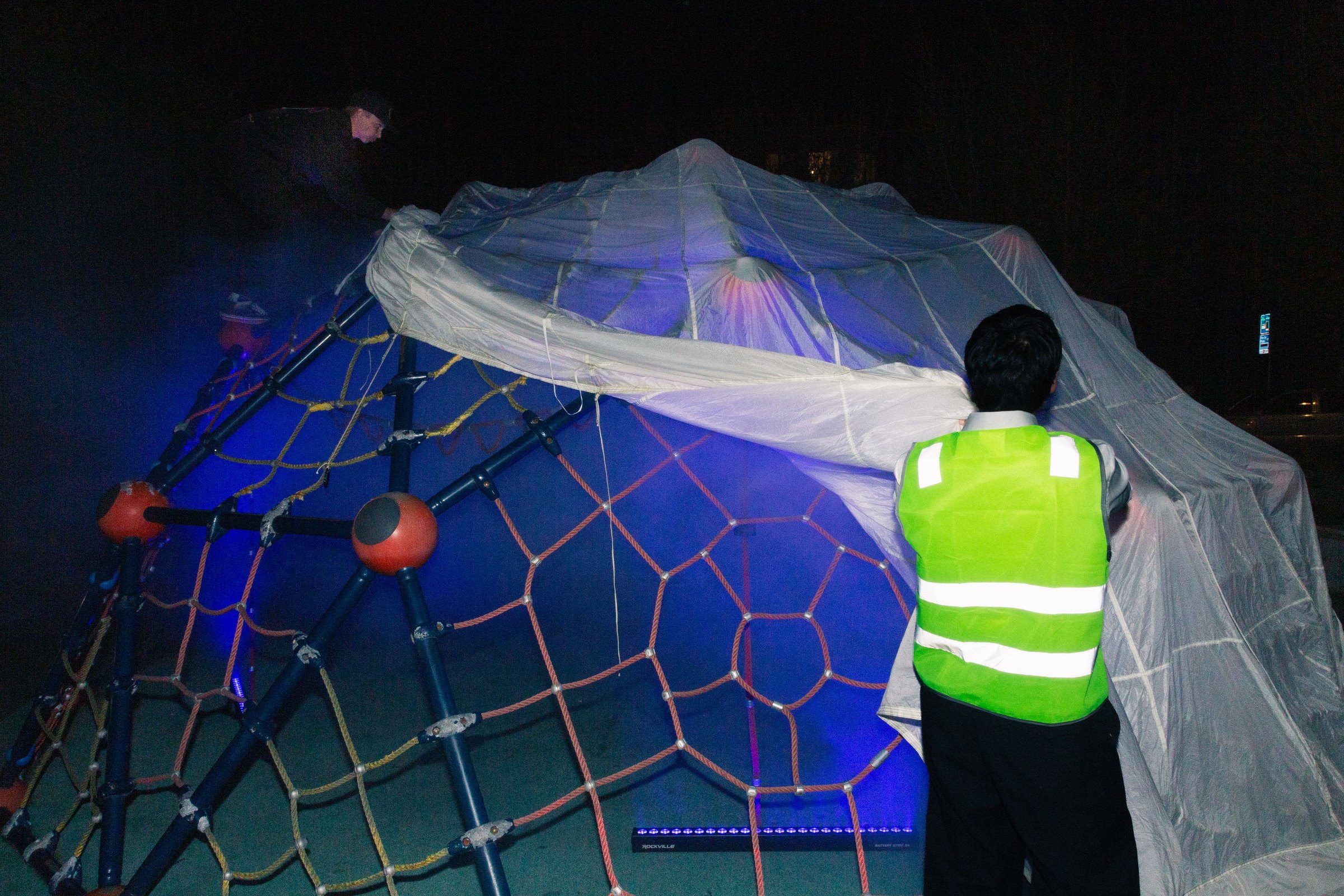 Crew in safety vests pulling the parachute off the jungle-gym frame after the show