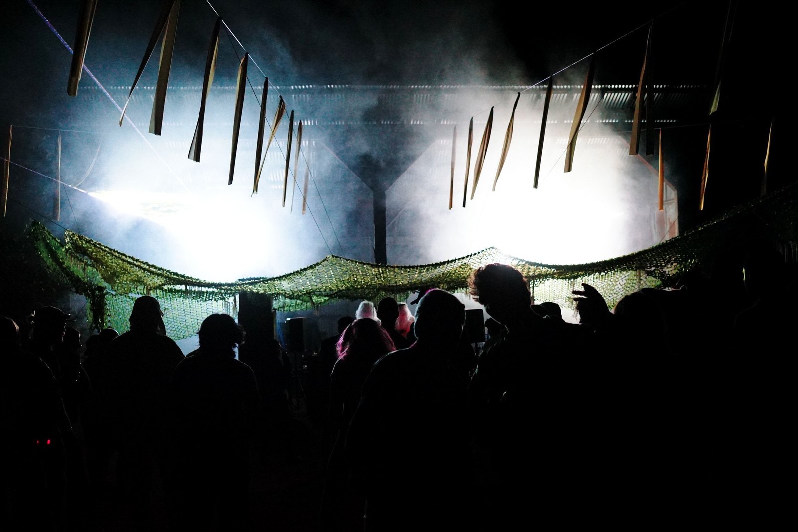 New Nostalgia in white ghillie suits DJing under the camouflage net at The Club, green lasers overhead