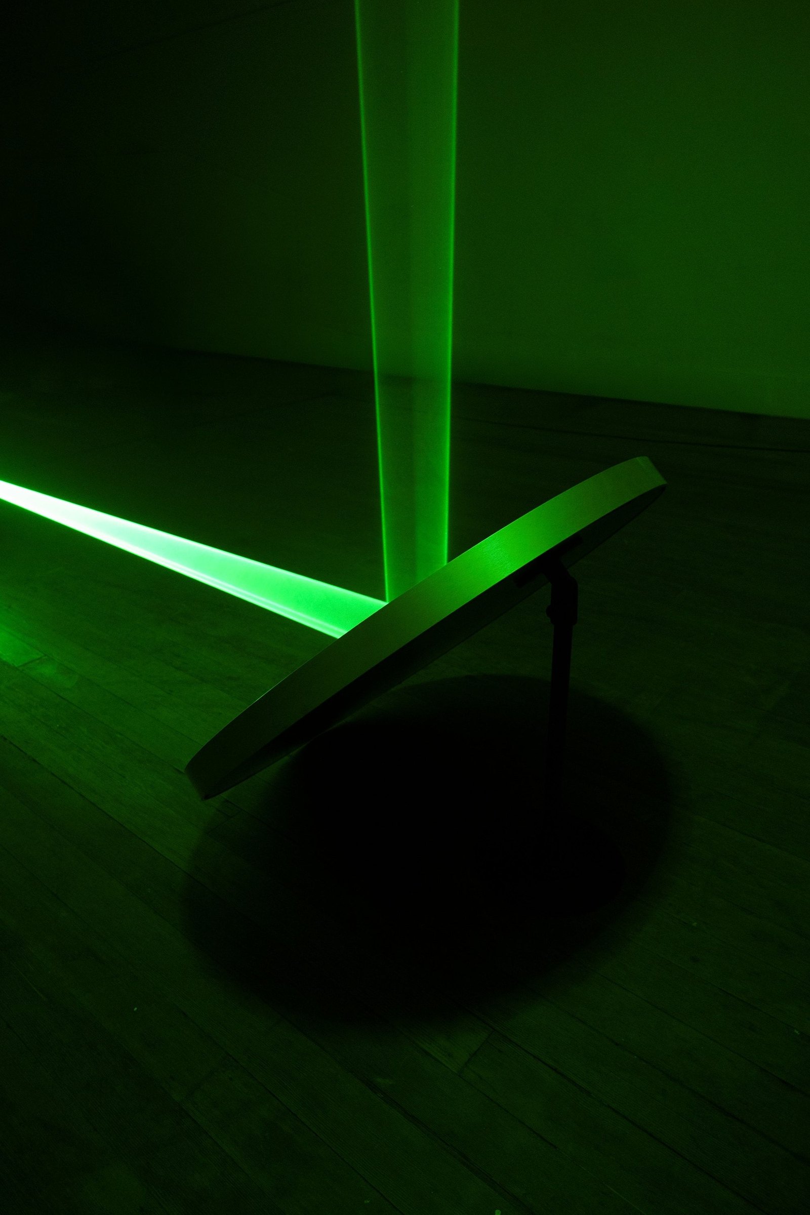 Close view of the green beam striking the round mirror on the podium during setup